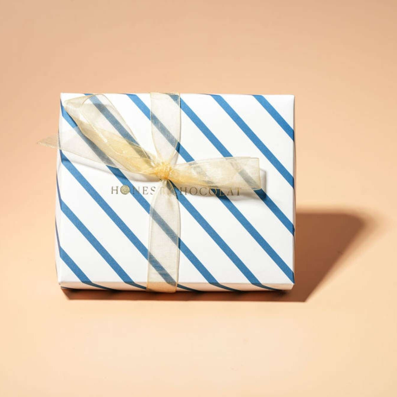 Gift box with blue and white striped pattern and a bow on a beige background