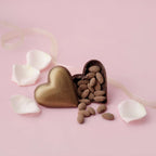 Heart-shaped chocolate box with almonds on a pink background