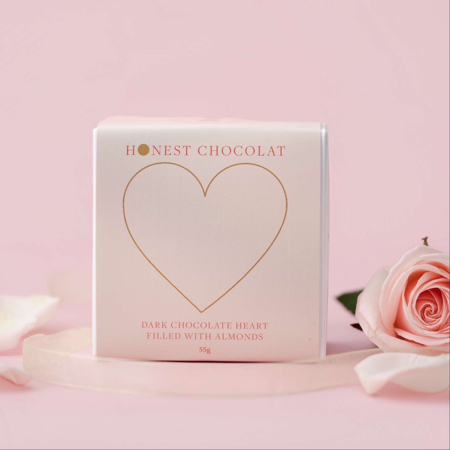 Honest Chocolat chocolate heart packaging on a pink background with roses.